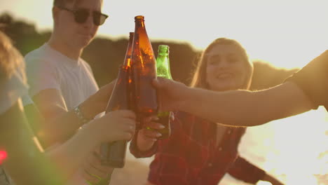 Company-of-young-people-celebrate-the-end-of-the-semester-with-beer.-This-is-carefree-summertime.-They-clink-and-drink-beer-on-the-open-air-party.